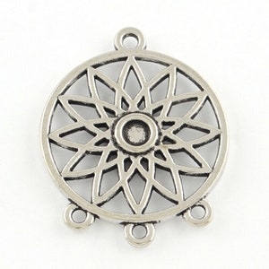 Könnte beinhalten: Silberfarbener Metall-Anhänger mit kreisförmigem Design und einem mandalaartigen Muster. Der Anhänger hat drei Ösen zum Anbringen an Schmuck oder anderen Bastelarbeiten.