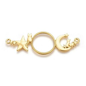 Peut inclure: Breloque en métal doré représentant une lune croissante avec un chat assis dessus, une étoile avec un chat assis dessus et un cercle. Le breloque a une boucle à chaque extrémité pour l'attacher à un collier ou un bracelet.