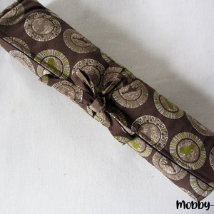 Könnte beinhalten: Eine braune Stoffrolle mit einem grün-weißen Muster aus Kreisen. Die Rolle ist mit einem braunen Band gebunden.