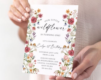 May include: A floral-themed first birthday party invitation with a watercolour design featuring a wreath of pink, red, and yellow flowers. The text reads "Our Little Wildflower is Turning One!" and includes details for the party, such as the date, time, location, and RSVP information.