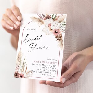 May include: A white bridal shower invitation with a pink and white floral design and the text "Join us for Bridal Shower honoring Kristen Larson Saturday, May 18, 2023 from 12-4pm Olive & Fig Bistro 3546 South Shore Drive Temecula, CA"