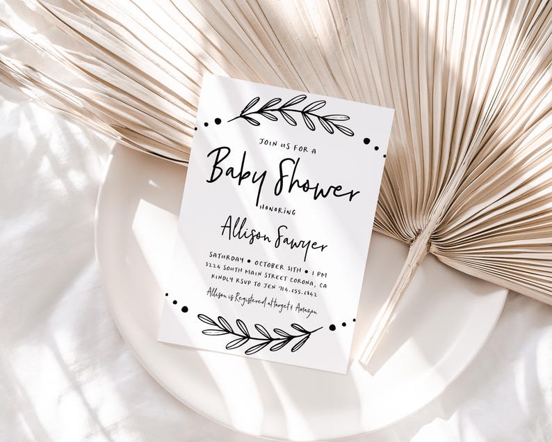 May include: A white baby shower invitation with black calligraphy text. The text reads "Join us for a Baby Shower honoring Allison Sawyer" and includes the date, time, and location of the event. The invitation is decorated with simple black floral illustrations.