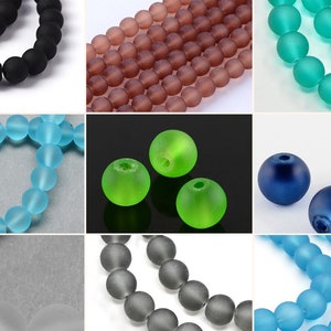 May include: A collection of round, matte-finish beads in various colours including black, brown, teal, light blue, bright green, dark blue, translucent white, and grey, arranged in a grid of nine separate sections showing individual and strung beads.