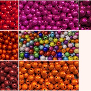 Op de afbeelding: Een verzameling ronde, gladde en glanzende kralen weergegeven in een raster van zeven afzonderlijke secties. De kralen worden getoond in effen kleuren, waaronder felrood, magenta, dieppaars, koper, oranje en een gemengd assortiment van kleuren.