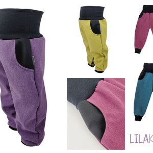Könnte beinhalten: Weiche, farbenfrohe Hosen mit hohem, schwarzem Bund und passenden Bündchen. Die Hosen sind in Lila, Gelbgrün, Rosa und Türkis erhältlich. Jede Hose hat eine schwarze Tasche an der Seite. Der Markenname "LILAKIND" ist unten rechts sichtbar.