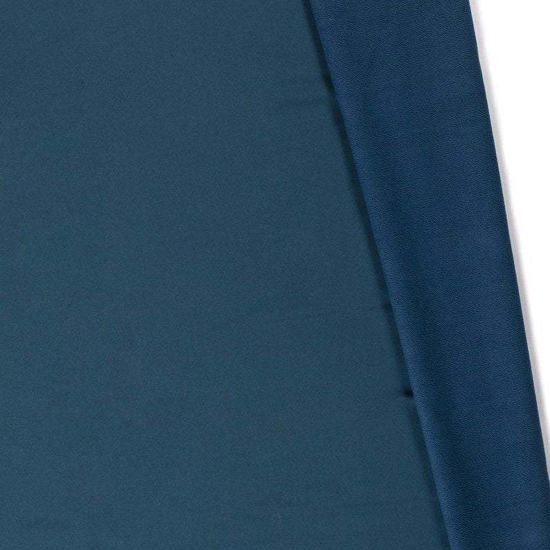 May include: Two pieces of fabric, one a dark teal blue and the other a slightly darker blue, are folded over each other. The fabric is smooth and has a slight sheen.