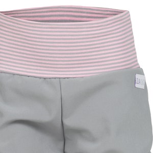 May include: Gray shorts with a pink and gray striped waistband. The shorts have a small white label with the text "SLACKZ" on the right side.