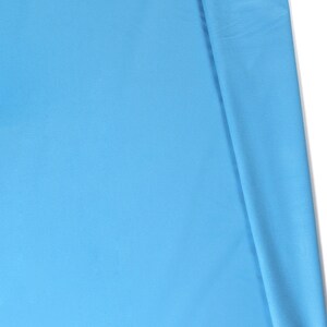 May include: A close-up of a light blue fabric folded in half. The fabric has a smooth, even texture.