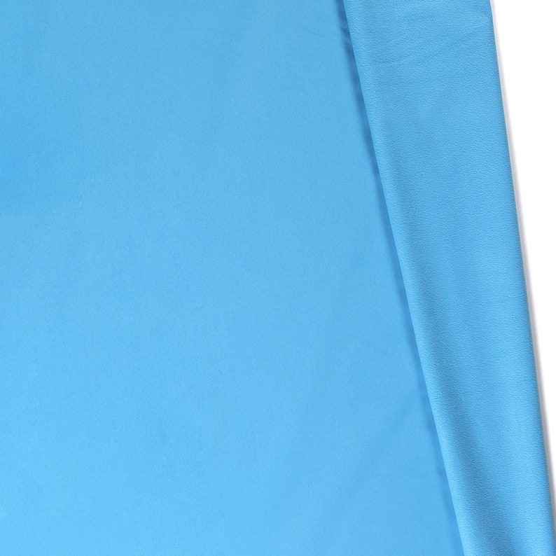 May include: A close-up of a light blue fabric folded in half. The fabric has a smooth, even texture.