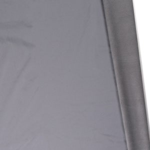 May include: A close-up of a piece of gray fabric. The fabric is smooth and has a slight sheen. The fabric is folded over on itself, revealing a darker gray underside.