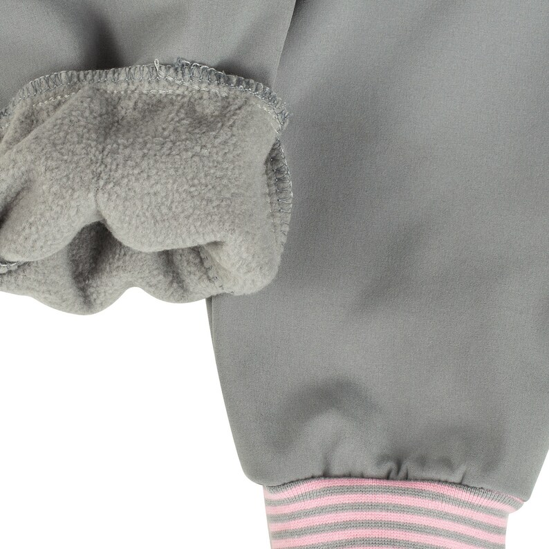 May include: Gray sweatshirt with a fleece lining on the inside of the cuff. The cuff has a pink and gray striped band.