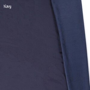 May include: A close-up of a navy blue fabric. The fabric is smooth and has a slight sheen. The text "Navy" is visible in the top left corner of the image.