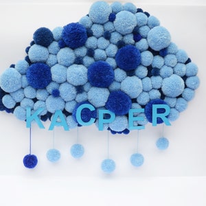 May include: A blue pom-pom cloud with the name "KAPER" spelled out in blue letters hanging from it. The cloud is made of many small blue pom-poms.