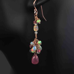 Pode incluir: Um par de brincos pendentes com uma gota de pedra preciosa rosa, contas de opala e granada e fio de ouro.