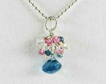 May include: A silver necklace with a pendant featuring a cluster of pink, blue, and white gemstones. The pendant is shaped like a flower with a teardrop-shaped blue gemstone hanging from the center.