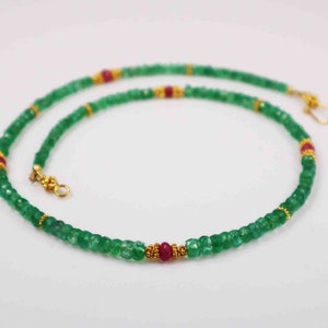 Puede incluir: Un collar de piedras preciosas de esmeralda verde con acentos de rubí rojo y cuentas doradas.