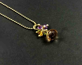May include: A gold chain necklace with a pendant featuring a large brown gemstone surrounded by smaller purple, green, and yellow gemstones.