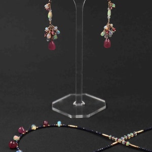 Peut inclure: Un ensemble de boucles d'oreilles et un collier avec un m&eacute;lange de pierres pr&eacute;cieuses roses, blanches et bleues. Les boucles d'oreilles sont de style pendantes et le collier est une cha&icirc;ne d&eacute;licate avec une vari&eacute;t&eacute; de pierres pr&eacute;cieuses.