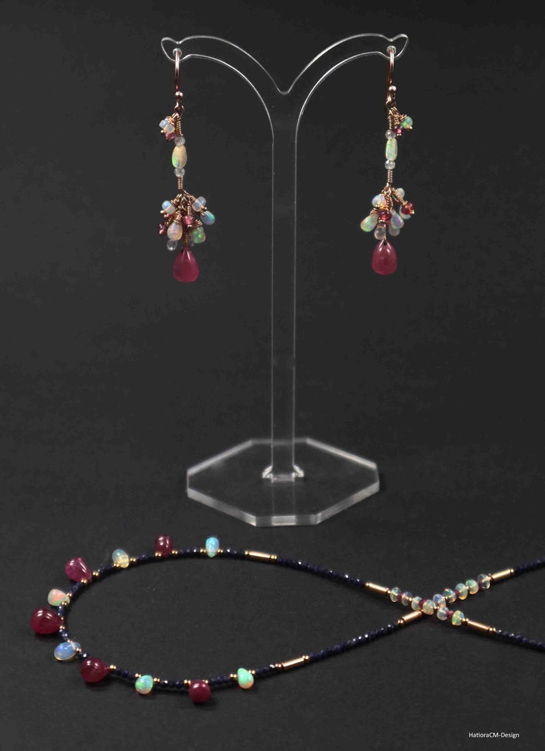 Peut inclure: Un ensemble de boucles d'oreilles et un collier avec un m&eacute;lange de pierres pr&eacute;cieuses roses, blanches et bleues. Les boucles d'oreilles sont de style pendantes et le collier est une cha&icirc;ne d&eacute;licate avec une vari&eacute;t&eacute; de pierres pr&eacute;cieuses.