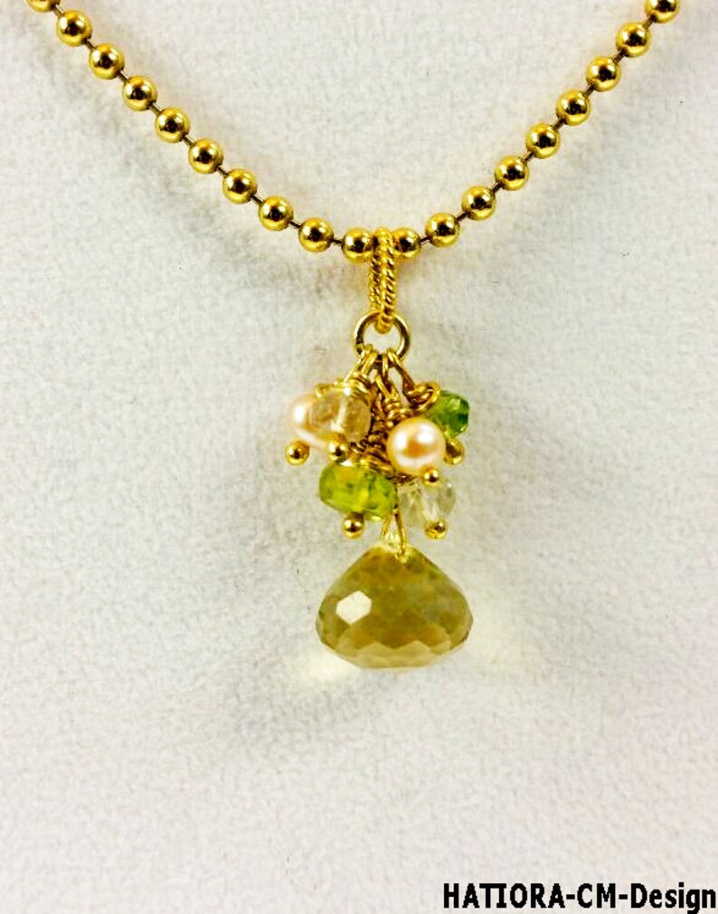 May include: A gold chain necklace with a pendant featuring a cluster of green and pink gemstones and a large, faceted, yellow gemstone.