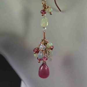 Peut inclure: Boucles d'oreilles pendantes en or rose avec un groupe d'opales roses et blanches et une seule pierre rose en forme de larme.