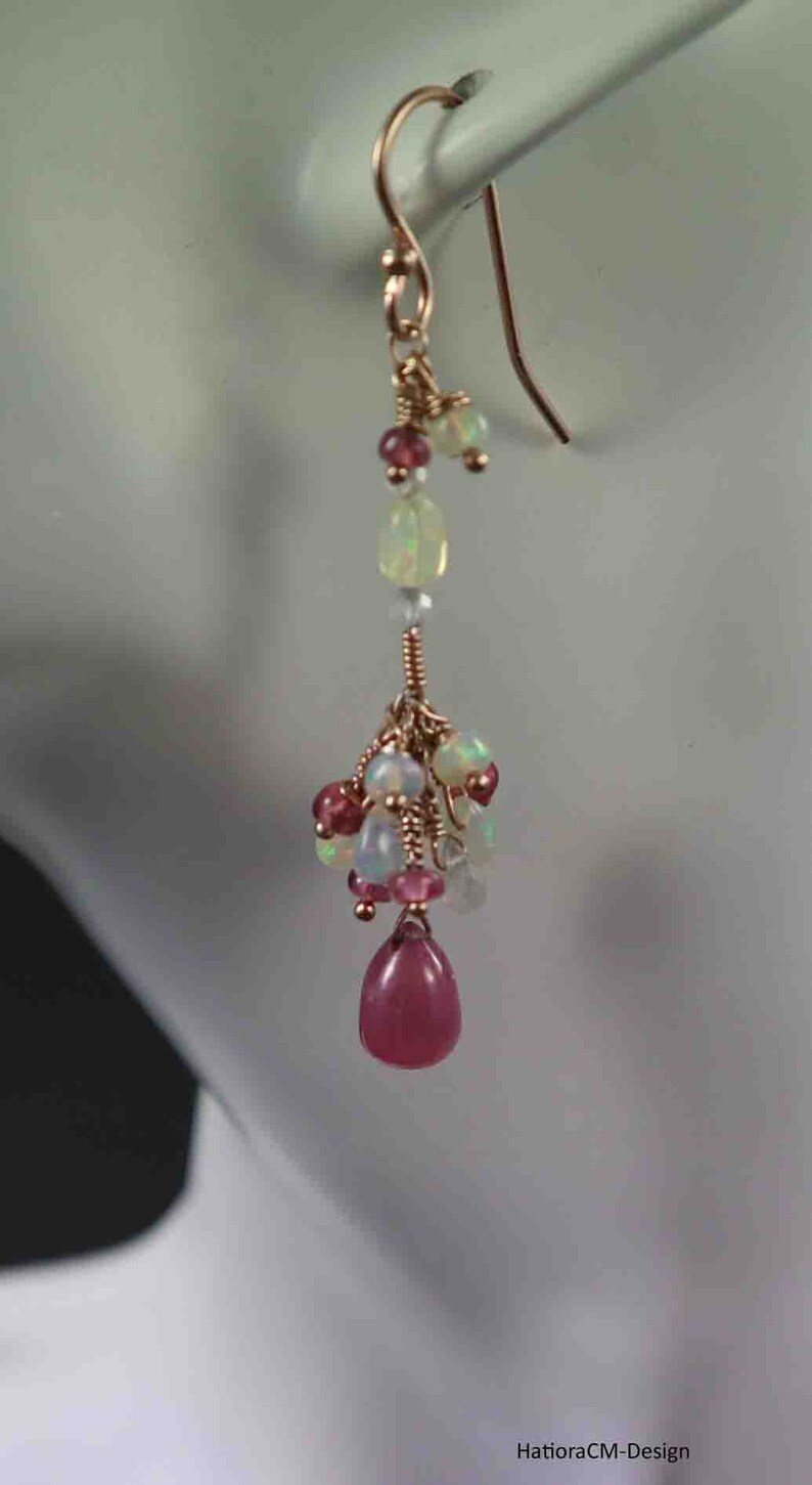 Peut inclure: Boucles d'oreilles pendantes en or rose avec un groupe d'opales roses et blanches et une seule pierre rose en forme de larme.