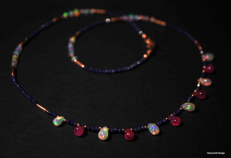 May include: A necklace made of blue and copper beads with teardrop-shaped opal and ruby gemstones.