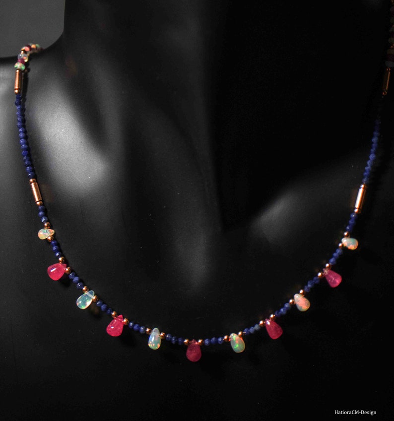 May include: A delicate necklace with alternating pink and white teardrop-shaped gemstones, separated by small blue beads and gold spacers.