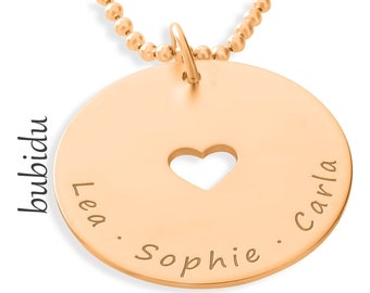 May include: Gold necklace with a round pendant featuring a heart cutout and the names "Lea", "Sophie", and "Carla" engraved around the edge.