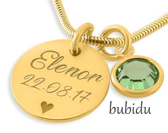 Op de afbeelding: Gouden ketting met een ronde hanger gegraveerd met de naam "Elenor" en de datum "22.08.17". Een kleine groene kristallen hanger hangt onder de hanger. De merknaam "bubidu" is onder de hanger gedrukt.