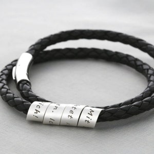 Könnte beinhalten: Schwarzes Lederarmband mit silbernen Perlen, die mit Wörtern graviert sind. Die Wörter auf den Perlen sind "Mit", "Herz", "en", "Ich!"