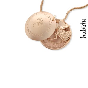 Puede incluir: Collar de oro con un medall&oacute;n que tiene un peque&ntilde;o amuleto de &aacute;ngel y un amuleto en forma de coraz&oacute;n. El medall&oacute;n est&aacute; grabado con el nombre "Penelope" y la fecha "08.07.2018". El amuleto en forma de coraz&oacute;n est&aacute; grabado con el texto "Keine Angst, du bist stark!" que se traduce como "No tengas miedo, eres fuerte!"