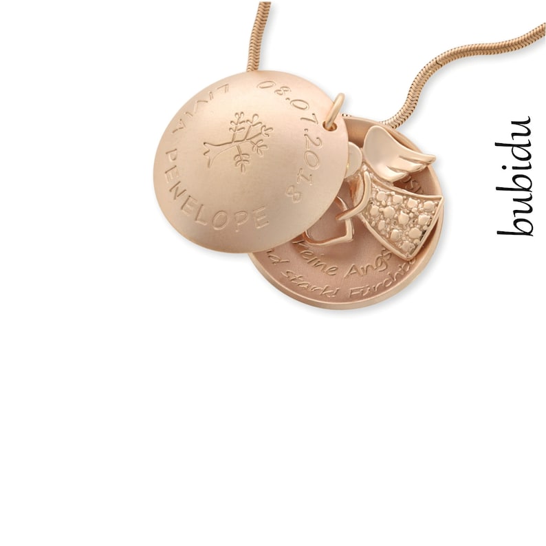Puede incluir: Collar de oro con un medall&oacute;n que tiene un peque&ntilde;o amuleto de &aacute;ngel y un amuleto en forma de coraz&oacute;n. El medall&oacute;n est&aacute; grabado con el nombre "Penelope" y la fecha "08.07.2018". El amuleto en forma de coraz&oacute;n est&aacute; grabado con el texto "Keine Angst, du bist stark!" que se traduce como "No tengas miedo, eres fuerte!"
