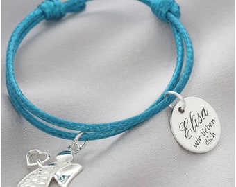May include: A turquoise braided cord bracelet with a silver charm featuring an angel holding a heart and a round tag with the text "Elisa wir lieben dich".
