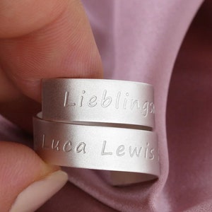 Può includere: Due anelli d'argento con le parole "Lieblings" e "Luca Lewis" incise.