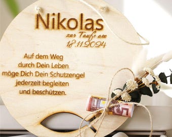 Puede incluir: Una placa de madera con el nombre Nikolas, la fecha 18.11.2024 y el texto "zur Taufe am" (para el bautismo el). La placa también tiene el texto "Auf dem Weg durch Dein Leben. möge Dich Dein Schutzengel jederzeit begleiten und beschützen." (En el camino a través de tu vida. Que tu ángel de la guarda te acompañe en todo momento y te proteja.)