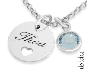May include: Silver necklace with a round pendant that says "Thea" with a heart cut out and a small light blue crystal charm.