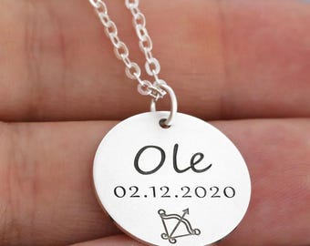 Może przedstawiać: Srebrny naszyjnik z okrągłym wisiorem, na którym widnieje napis "Ole 02.12.2020" oraz symbol zodiaku Strzelca.