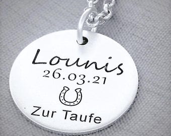 Puede incluir: Collar de plata con un colgante redondo que dice "Lounis 26.03.21" con un símbolo de herradura y las palabras "Zur Taufe" debajo.