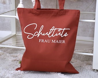 May include: A rust-colored tote bag with white text that reads "Schultüte FRAU MAIER".