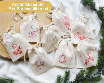 May include: A collection of eight beige drawstring bags, each adorned with a unique Christmas-themed illustration and a number from 1 to 8. The bags feature festive designs like a fox, snowman, and reindeer. The text "Adventskalender Bio-Baumwollbeutel" is visible.