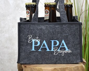May include: A gray felt six-pack beer carrier with black handles and the text "Bester Papa Benjamin" in blue and white lettering.
