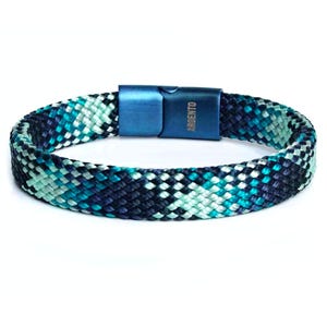 Könnte beinhalten: Ein geflochtenes Armband in Blau, Grün und Weiß mit einem blauen Metallverschluss. Der Verschluss trägt die eingravierte Aufschrift "ARGENTO".