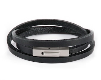 May include: A black leather bracelet with a silver clasp. The bracelet is made of three strands of leather.