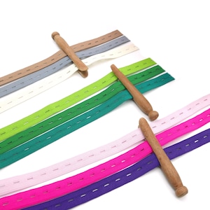 Peut inclure: Assortiment d'élastiques colorés avec des boutons en bois. L'élastique est disponible en violet, rose, fuchsia, rose clair, vert, sarcelle et gris. L'élastique a des coutures espacées uniformément.