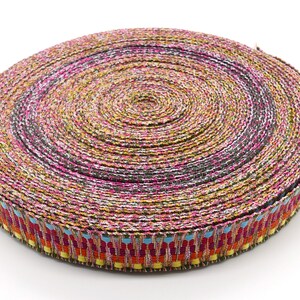 Peut inclure: Un rouleau de ruban d&eacute;coratif avec un motif tiss&eacute;. Le ruban pr&eacute;sente un m&eacute;lange de couleurs, dont le rose, le jaune, le noir et le bleu. Le bord du ruban a une bordure &agrave; motifs avec des accents rouges, oranges, jaunes et bleus.