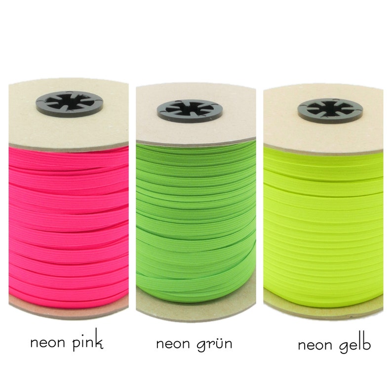 May include: Three spools of neon elastic cord. The spools are wound with pink, green, and yellow elastic cord. The spools are labeled "neon pink", "neon gr&uuml;n", and "neon gelb".