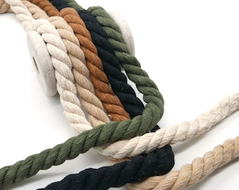 Peut inclure: Gros cordes torsadées de différentes couleurs, crème, beige, marron, noir et vert olive. Les cordes sont disposées en rangée, avec une bobine en bois en arrière-plan. Idéal pour l'artisanat ou la décoration.
