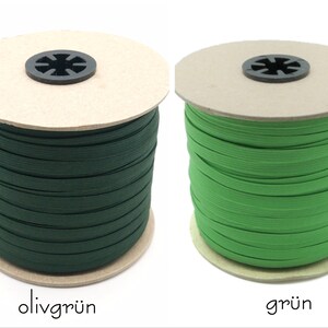 May include: Two spools of elastic cord, one green and one olive green. The spools are made of cardboard and have a label with the color name in German.