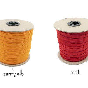 May include: Two spools of elastic cord, one orange and one red. The spools are labeled "senfgelb" and "rot".